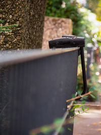 Close-up of rusty metal fence against wall in yard