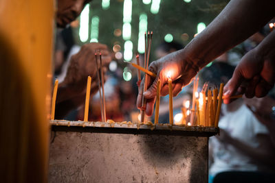 Close-up of hands burning candles in temple