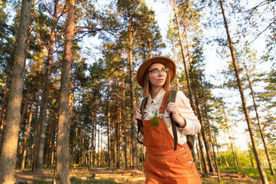 Woman botanist on ecological hiking trail in summer. naturalist exploring wildlife and ecotourism.