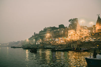 River by illuminated city buildings against clear sky