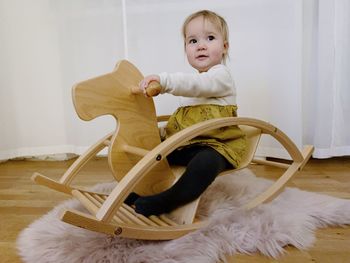 Portrait of cute baby sitting on a rocking horse at home