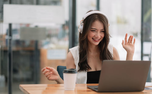 Young woman using mobile phone at table
