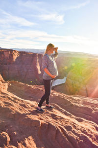 Full length of pregnant woman standing on rock at horseshoe bend against sky