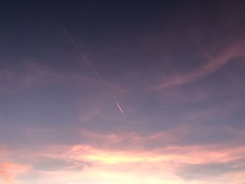 Low angle view of vapor trail in sky during sunset