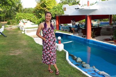 Portrait of smiling woman standing by swimming pool