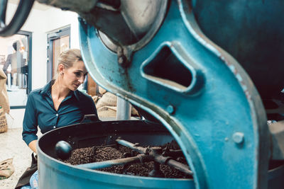 Woman looking at coffee beans in machinery