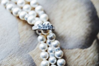 Close-up of engagement ring and pearl necklace