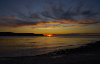 Scenic view of sea against dramatic sky during sunset