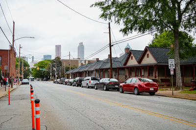 Cars on road by buildings in city against sky