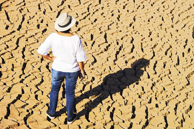 Rear view of woman standing on drought land
