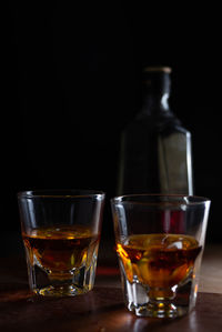 Close-up of whiskey glasses on table against black background