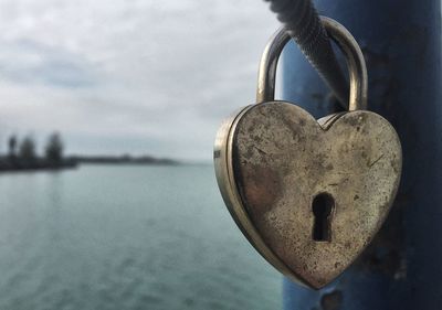 Close-up of padlocks on heart shape against sky