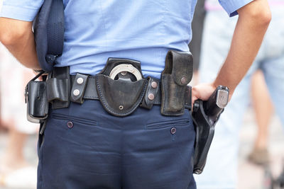 Midsection rear view of police man with belt with handcuffs and gun