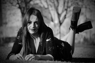 Portrait of young woman lying on field at park