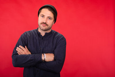 Portrait of young man standing against red background