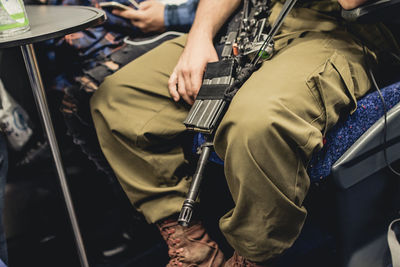 Low section of man with rifle sitting on seat