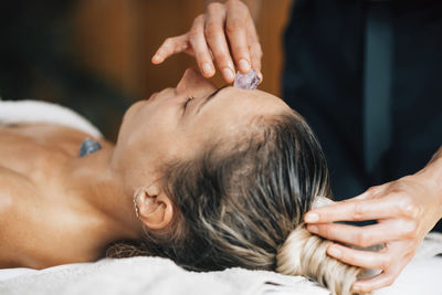 Ayurvedic practitioner using gemstones and crystals for healing female patient chakras