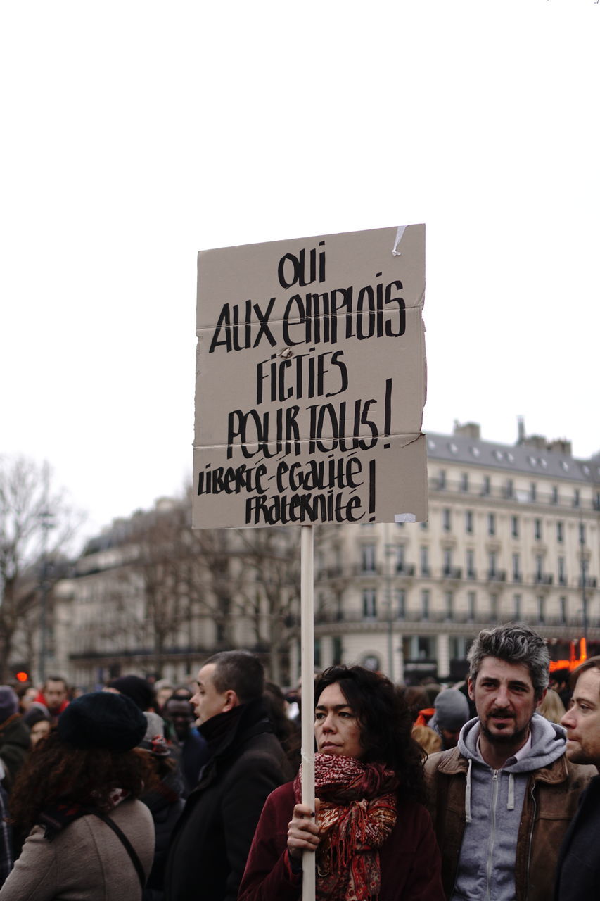 communication, text, western script, protest, real people, placard, day, outdoors, protestor, women, men, architecture, togetherness, clear sky, young women, building exterior, young adult, people