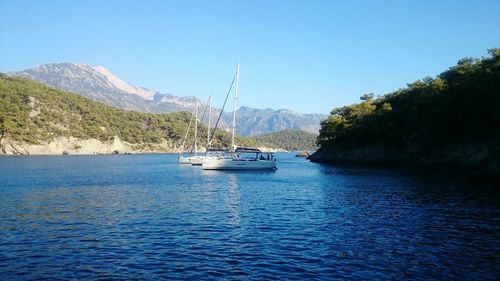 Boats sailing in sea against clear sky