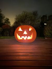 Close-up of illuminated pumpkin against trees during halloween