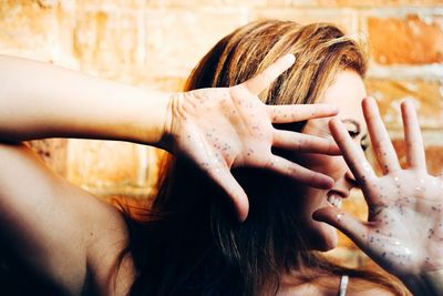 Close-up of cheerful woman showing sequins on hands while looking away