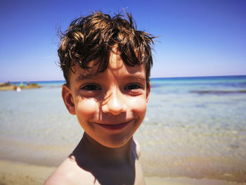 Portrait of happy boy at beach against sky
