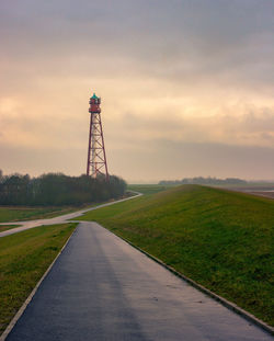 Tower on land against sky during sunset