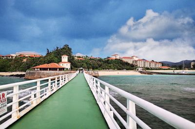 Bridge over sea by buildings in city against sky