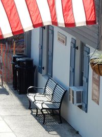 Empty chairs and tables at sidewalk cafe amidst buildings in city