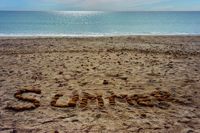 Text on sand at beach against sky