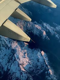 High angle view of airplane flying over snowcapped mountains