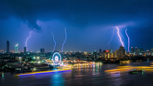 Lightning over illuminated cityscape against sky
