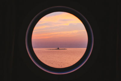Scenic view of sea against sky during sunset seen through window