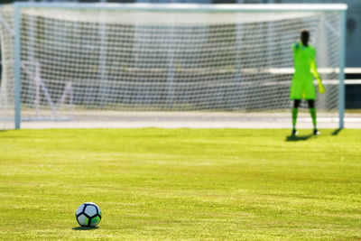 Soccer ball on playing field against goal post