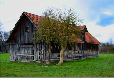 Barn by house on field against sky