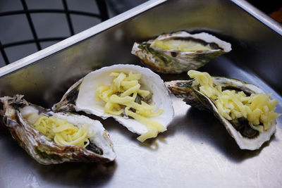 Shredded cheese on fresh oysters on a tray prepared for bbq