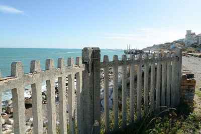 Panoramic view of wooden posts in sea against sky