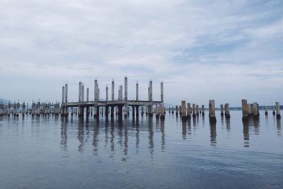 Wooden posts in sea against sky