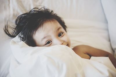 Portrait of smiling baby wrapped in white blanket