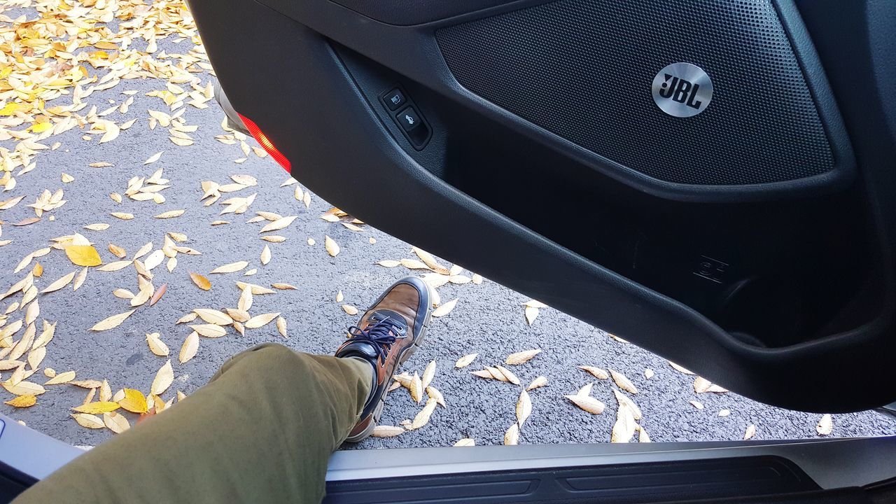 car, real people, land vehicle, one person, high angle view, day, low section, black color, shoe, human leg, men, outdoors, close-up, human body part