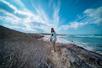 Woman standing on beach against sky
