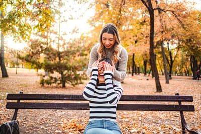 Young woman sitting on bench in park