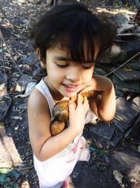 High angle view of cute girl holding coconuts while standing outdoors