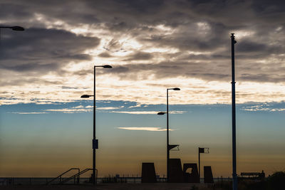 Street lights against dramatic sky during sunset