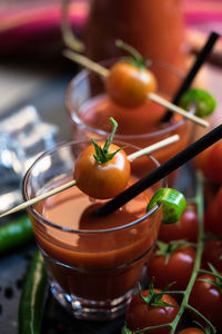 Close-up of tomato juices with green chili peppers and cherry tomatoes on table