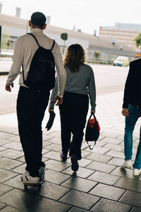 Rear view of friends walking on street in city