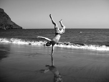 Full length of man skateboarding on beach against sky