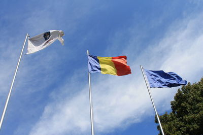 Low angle view of waving flags against sky