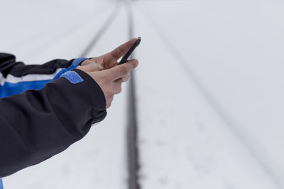 Midsection of man holding mobile phone against wall