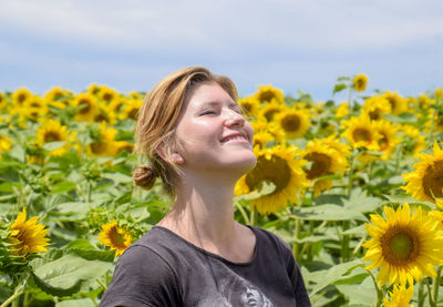 Woman standing against sunflowers field